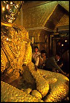 Adding golden leaves to the venerated Mahamuni image. Mandalay, Myanmar