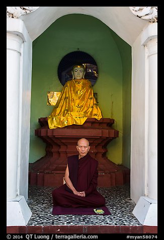 Monk meditating in alcove with Buddha statue, Shwedagon Pagoda. Yangon, Myanmar