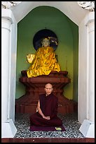 Monk meditating in alcove with Buddha statue, Shwedagon Pagoda. Yangon, Myanmar