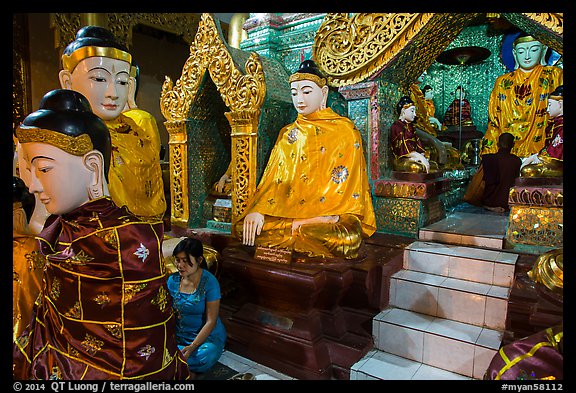 Woman and monk in pavillion surrounded by Buddha statues. Yangon, Myanmar (color)