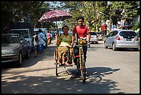 Woman holding unbrella against sun while riding Trishaw. Yangon, Myanmar ( color)