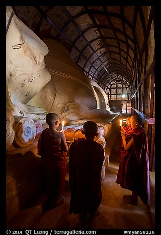 Novices standing with candles next to Shin Bin Thal Yaung reclining Budddha. Bagan, Myanmar (color)