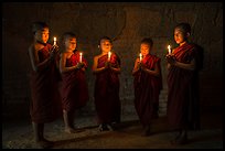 Five novices standing in circle inside temple with candles. Bagan, Myanmar ( color)