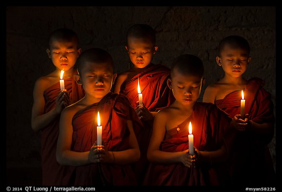Young buddhist monks holding candles with eyes closed. Bagan, Myanmar (color)