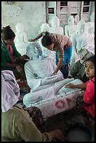 Women polishing buddha statue. Mandalay, Myanmar ( color)