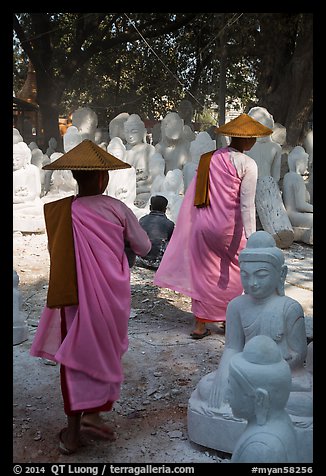 Nuns walk between buddha statues on Marble street. Mandalay, Myanmar (color)