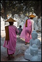 Nuns walk between buddha statues on Marble street. Mandalay, Myanmar ( color)