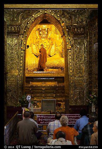 Monk applying gold leaf to Buddha statue in Mahamuni Pagoda. Mandalay, Myanmar (color)