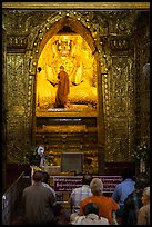 Monk applying gold leaf to Buddha statue in Mahamuni Pagoda. Mandalay, Myanmar ( color)