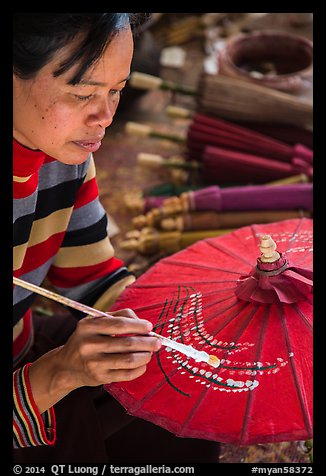 Woman painting the paper sun umbrellas carried by the monks. Pindaya, Myanmar (color)