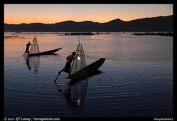 Leg-rowing Intha fishermen with lanterns at dusk. Inle Lake, Myanmar (color)