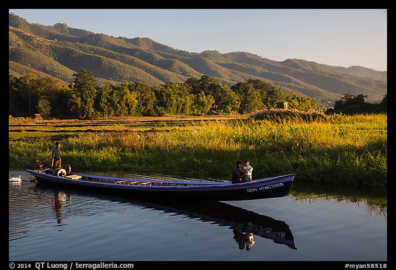 Woman riding with child in front of boat in Maing Thauk Village. Inle Lake, Myanmar (color)