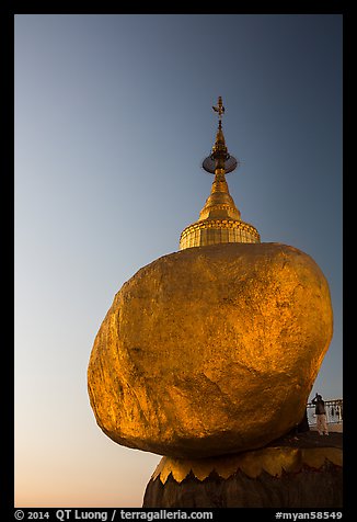 Pilgrim prays to the gleaming Golden Rock at sunset. Kyaiktiyo, Myanmar (color)