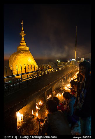 Pilgrims light up candles behind the Golden Rock at dusk. Kyaiktiyo, Myanmar (color)