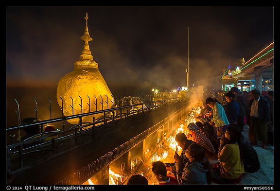 Pilgrims pray with candles behind the Golden Rock. Kyaiktiyo, Myanmar (color)