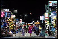 Girls carry offering material up the stairs of Potemkin village at night. Kyaiktiyo, Myanmar ( color)