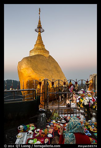 Pilgrim and food offerings behind Golden Rock at dawn. Kyaiktiyo, Myanmar (color)