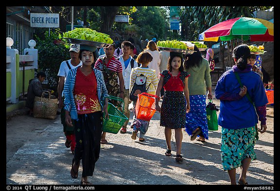 Women walk with platers of food on their heads. Kyaiktiyo, Myanmar (color)