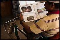 Cyclo driver looking at picture of QT Luong tour group in newspaper. Bago, Myanmar ( color)