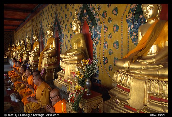 Monks sitting below row of buddha images, Wat Arun. Bangkok, Thailand (color)
