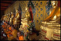 Monks sitting below row of buddha images, Wat Arun. Bangkok, Thailand (color)