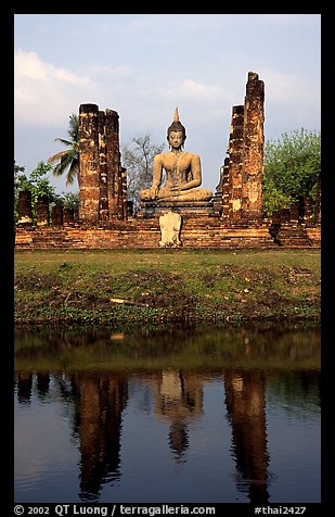 Buddha image reflected in moat, morning, Wat Mahathat. Sukothai, Thailand (color)