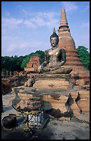 Classic sitting Buddha image and tiered, bell-shaped chedi. Sukothai, Thailand