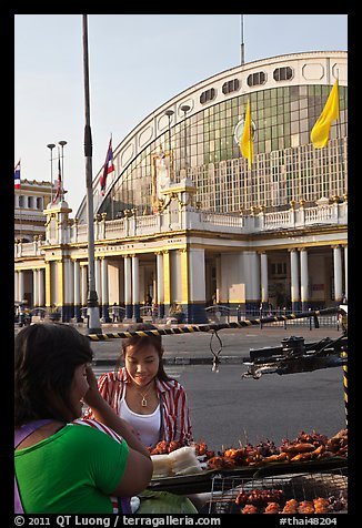 Woman buying food at stall in front of station. Bangkok, Thailand (color)