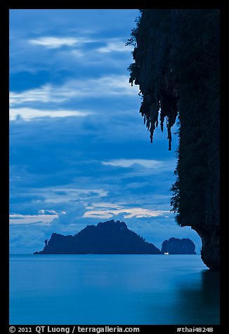 Limestone crag with stalactite, distant islet, boat light, Railay. Krabi Province, Thailand