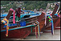 Row of boats, fisherman standing, Ko Phi Phi. Krabi Province, Thailand