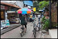 Woman riding bicycle with unbrella, Tonsai village, Ko Phi-Phi Don. Krabi Province, Thailand