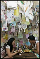 Couple eating Pad Thai below notes of praise left by customers, Ko Phi Phi. Krabi Province, Thailand