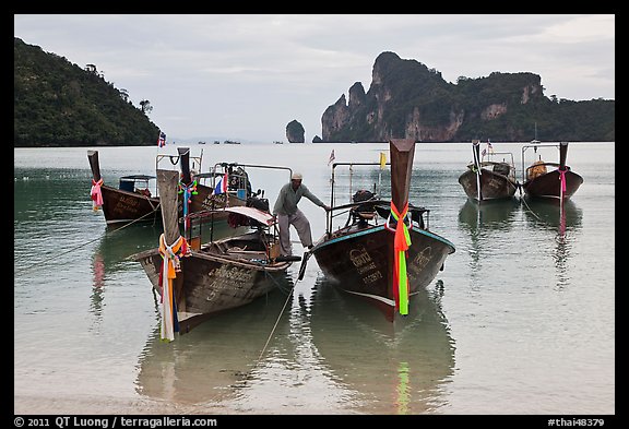 Man stepping on boats, Ao Lo Dalam, Ko Phi-Phi Don. Krabi Province, Thailand (color)