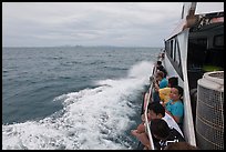 Passengers sitting on side of boat. Krabi Province, Thailand