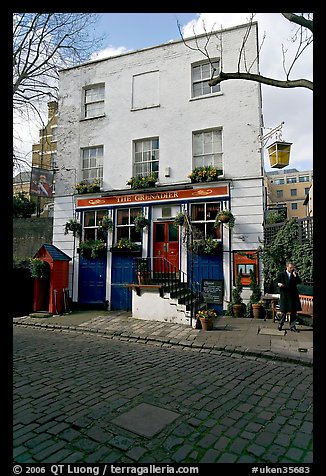 Cobblestone mews, pub, and man standing outside. London, England, United Kingdom