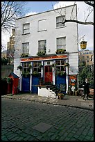 Cobblestone mews, pub, and man standing outside. London, England, United Kingdom