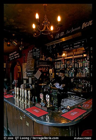 Woman cleaning glass at the bar, pub The Grenadier. London, England, United Kingdom