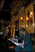 Man reading newspaper in front of etched mirrors, pub Princess Louise. London, England, United Kingdom (color)