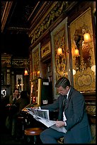 Man reading newspaper in front of etched mirrors, pub Princess Louise. London, England, United Kingdom