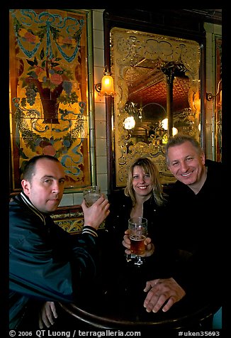Friends cheering up with a beer in front of echted glass and fine tiles of pub Princess Louise. London, England, United Kingdom