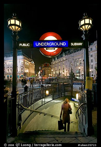 Woman with shopping bag entering subway at night, Piccadilly Circus. London, England, United Kingdom (color)