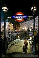 Woman with shopping bag entering subway at night, Piccadilly Circus. London, England, United Kingdom