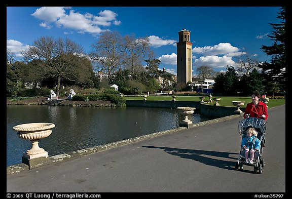Woman pushing stroller next to the lake. Kew Royal Botanical Gardens,  London, England, United Kingdom