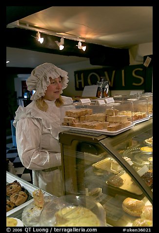 Woman wearing old-fashioned attire in a bakery, Lacock. Wiltshire, England, United Kingdom