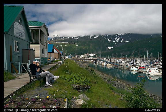 Couple sitting on bench by the harbor. Whittier, Alaska, USA (color)