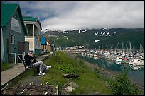 Couple sitting on bench by the harbor. Whittier, Alaska, USA