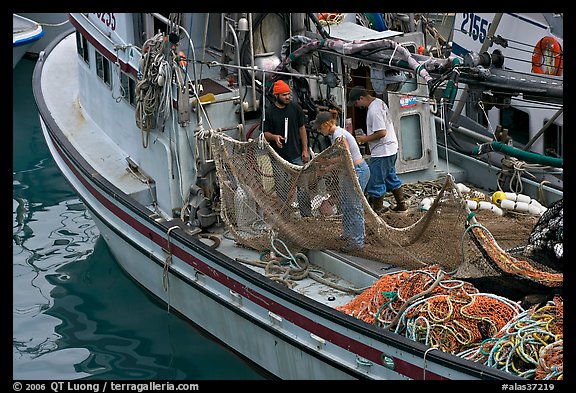 Fishermen repairing nets on fishing boat. Whittier, Alaska, USA