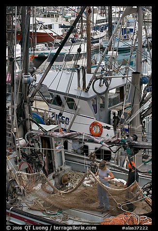 Man and woman repairing nets on fishing boat. Whittier, Alaska, USA