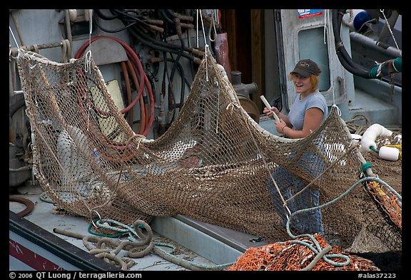 Woman repairing net on fishing boat. Whittier, Alaska, USA (color)