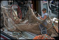 Woman repairing net on fishing boat. Whittier, Alaska, USA ( color)